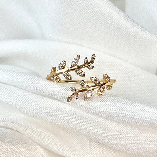 The Leaf Crown Encompassing Ring features a beautiful, nature-inspired design with delicate leaves encircling the finger, creating a crown-like effect. The intricate detailing and graceful leaf motifs evoke the beauty of nature, symbolizing growth, renewal, and the interconnectedness of life. This elegant ring offers a unique blend of sophistication and organic charm, perfect for those who appreciate nature's beauty and wish to wear a piece of timeless elegance. Whether worn as a statement piece or a subtle